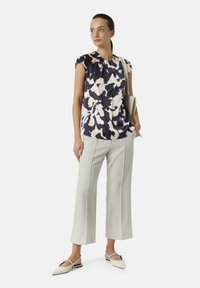 Floral navy and cream blouse with cap sleeves, paired with light grey wide-leg trousers and pointed flats, featuring a minimalist design.