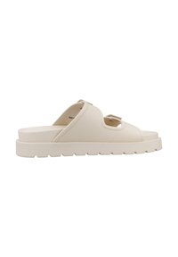 Beige instap sandaal met een gestructureerde bovenkant, open teen ontwerp en een dikke witte rubberen zool. Bevat snij-inzetten voor ventilatie.