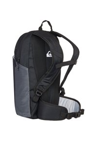 Svart och grå ryggsäck med justerbara remmar, nätdetaljer, sidofickor, dragkedjor och en böjd form för ergonomisk passform.