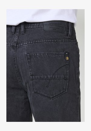 Jean en denim noir avec une coupe droite, doté de poches arrière, de détails de couture subtils et d'une étiquette sur la ceinture.
