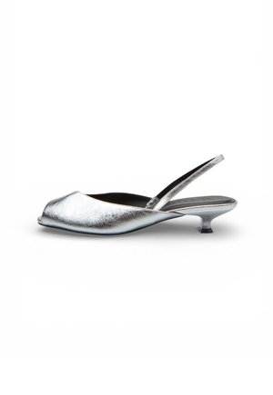 Scarpa slingback argento metallizzato con tacco kitten basso e curvo, punta aperta e appuntita, su sfondo bianco.