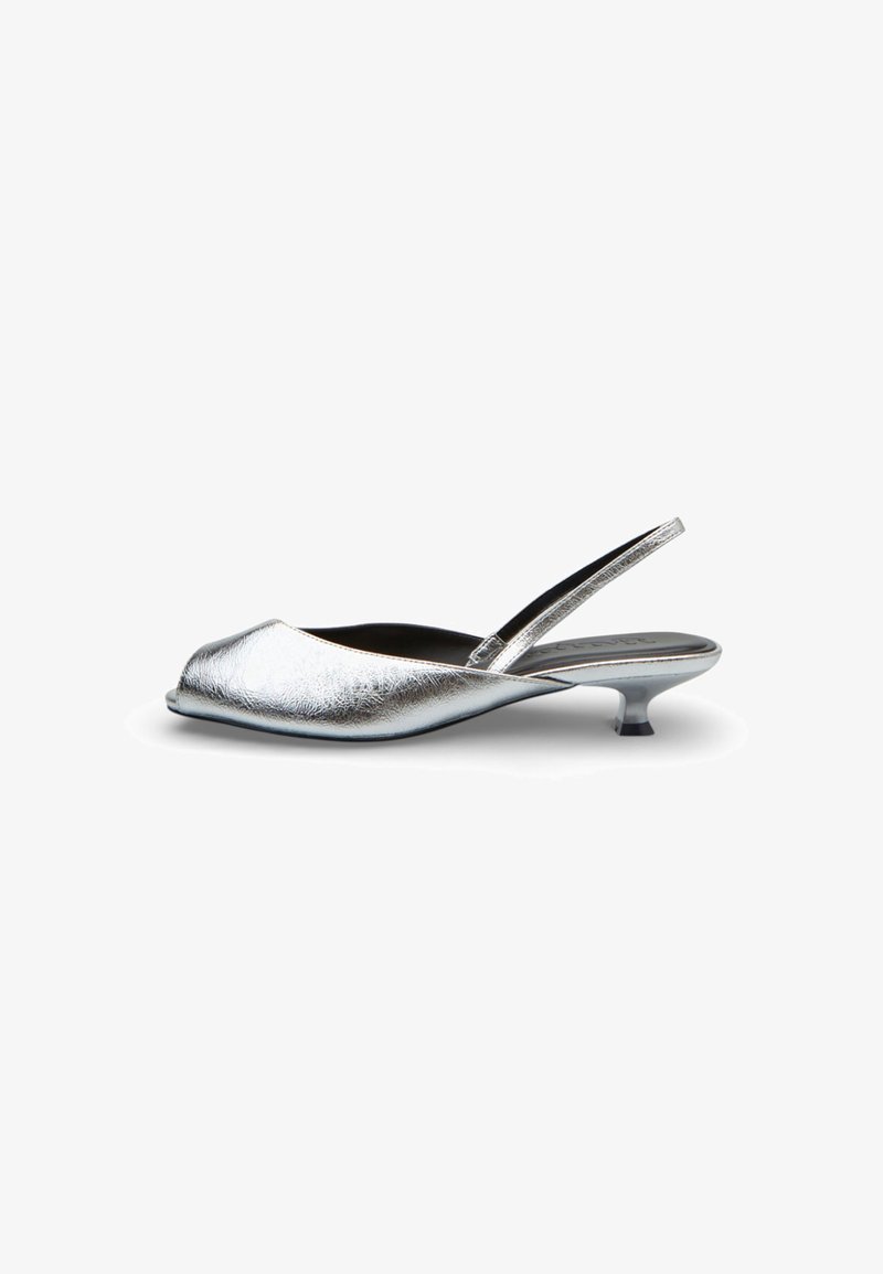 Zapato de tacón bajo tipo slingback metálico plateado con puntera abierta y tacón curvado bajo sobre fondo blanco.