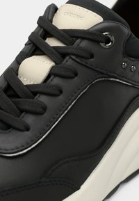 Μαύρο δερμάτινο αθλητικό παπούτσι με αντίθετες λευκές λεπτομέρειες, υφασμένα κορδόνια και ορατή ραφή. Διαθέτει στρογγυλεμένη μύτη και μινιμαλιστικό σχεδιασμό.