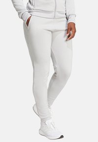 Light gray athletic pants made from a soft, stretchy material with fitted design, side pockets, and reinforced stitching accents.