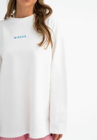 Witte langemouw t-shirt met blauwe geborduurde tekst "MIRONS." Gemaakt van zachte stof met een relaxed fit en verlaagde schouders.