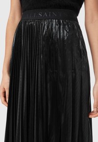 Musta laskostettu hame, jossa kiiltävä pinta. Leveä joustava vyötärönauha on kohokuvioitu tekstiillä "ALLSAINTS". Kangas laskeutuu tyylikkäästi.