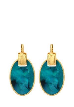 Boucles d'oreilles en or avec de grandes pierres précieuses ovales bleu-vert et crochets en or texturés, présentées sur un fond blanc.