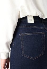 Ψηλές τζιν φούστα σε σκούρο μπλε με πορτοκαλί ραφές, διαθέτει ετικέτα που γράφει 'JDY' και δύο πίσω τσέπες. Απαλή υφή.