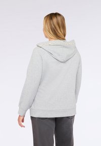 Felpa grigia con cappuccio, realizzata in un tessuto morbido, con dettagli decorativi in perle lungo la parte posteriore del cappuccio e una vestibilità comoda.