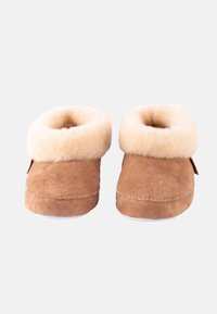 Bruna mockasiner i mocka med en beige ullkrage, rund tå och vita sulor. Har sömmar längs ovandelen och en sidetikett.