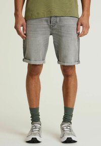 Lysegrå denim shorts med opsmøgte ben, båret med grønne sokker og grå sneakers. Stoffet har en let tekstur, og pasformen er afslappet.