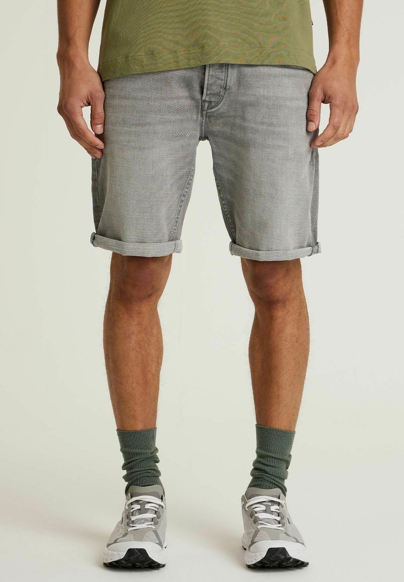 Lysegrå denim shorts med opsmøgte ben, båret med grønne sokker og grå sneakers. Stoffet har en let tekstur, og pasformen er afslappet.