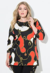 Schwarzes Shirt mit auffälligen roten und weißen abstrakten Mustern, die goldene Kettenmuster und Akzente aufweisen. Weicher Stoff und Dreiviertelärmel.