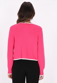 Suéter de punto rosa con manga larga, diseño corto, dobladillo y puños blancos en contraste, textura suave, vista trasera mostrada.