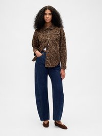 Πουκάμισο με σχέδιο λεοπάρ σε καφέ και μαύρο, συνδυασμένο με ψηλόμεσα μπλε τζιν με ίσια γραμμή και καφέ φλατ παπούτσια. Ομαλή υφή και άνετη εφαρμογή.