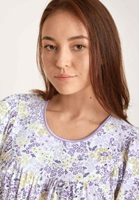 Top con stampa floreale nei colori viola, giallo e bianco. Tessuto morbido con scollatura rotonda e dettagli arricciati. Accentuato da delicate ricami.