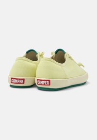 Gula kanvas sneakers med gröna accenter, platt krämfärgad sula, framträdande röd "CAMPER"-logotyp på hälen och snörningsdesign.