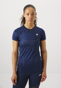 T-shirt atlético azul-marinho com mangas curtas, apresentando um padrão texturizado e detalhes claros. Logótipo no peito esquerdo. Tecido suave e elástico.