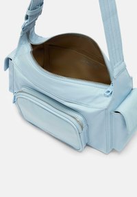 Lichtblauwe leren schoudertas met een buitentas, ritsluiting en gevoerde binnenkant. Voorzien van een gestructureerde band voor extra comfort.