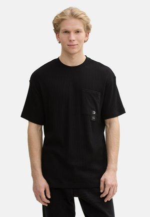 Zwarte, gestructureerde t-shirt met een ronde hals, korte mouwen en een voorzak met een klein label. Het materiaal lijkt zacht en ademend.