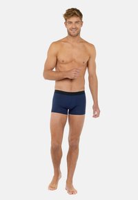 Marinblå boxerkalsonger med svart elastiskt midjeband, tillverkade av ett slätt tyg och med en figurnära design. Inga mönster eller detaljer.