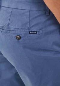 Pantalones cortos de algodón azul que cuentan con un bolsillo trasero visible, un cierre de botón y una pequeña etiqueta de marca con el nombre "Façonnable."