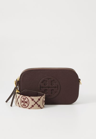 Brown leather crossbody bag with textured finish, featuring a circular logo and a patterned beige strap with maroon accents. Gold zipper hardware.