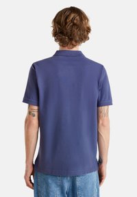 Polo de color navy con cuello, mangas cortas y una textura suave, con un dobladillo recto y aberturas laterales para mayor comodidad.