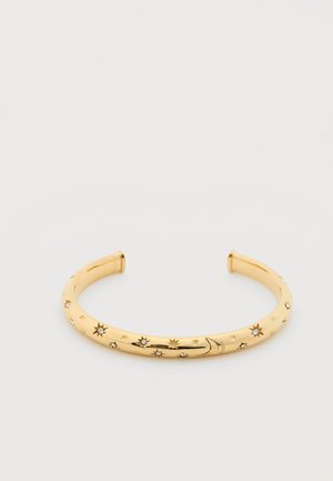 Gouden manchetarmband gegraveerd met sterren- en maanoarden, voorzien van kleine ingebedde kristallen langs het gebogen oppervlak.