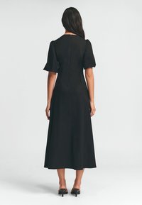 Schwarzes Midikleid mit kurzen Puffärmeln, einem taillierten Oberteil und einem ausgestellten Rock. Geschlossener Rücken mit einem unsichtbaren Reißverschluss. Glatte Stofftextur.