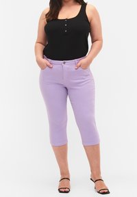 Musta ribattu toppi, jossa on kolme metallista nappia, yhdistettynä vaaleanliilan värisiin capri-housuihin, joissa on taskut ja istuva muotoilu.