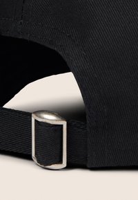 Cappello nero con tessuto strutturato, dotato di una fibbia in metallo argento su un cinturino nero sul retro. Dettagli cuciti visibili.