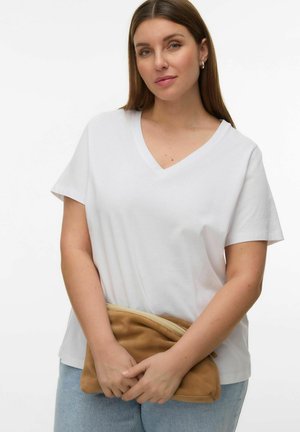 Woman with straight brown hair wearing a white V-neck t-shirt, light blue jeans, silver hoop earrings, holding a tan suede clutch bag.