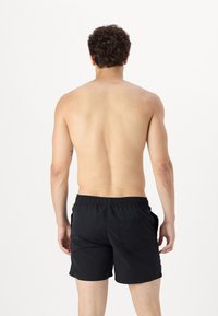 Zwarte zwembroek met een elastische tailleband en zijzakken, met een effen ontwerp en een lengte boven de knie. Gezien vanuit de achterkant.