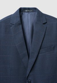 Blazer a quadri blu navy con colletto a lancia, chiusura con un solo bottone e taschino sul petto. Fodera interna liscia di colore coordinato.