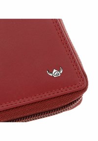 Coin d’un portefeuille en cuir et tissu rouge avec une fermeture éclair et un petit emblème argenté de casque viking.