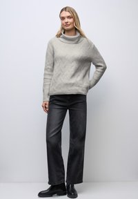 Pull tricoté texturé gris clair avec un col bénitier, associé à un jean noir taille haute à coupe droite et des bottines.