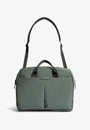 Sac de sport vert en softshell avec deux poches avant, poignées courtes et sangle d'épaule rembourrée réglable.
