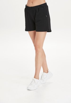 Sorte bomulds shorts med elastisk talje, der har sidelommer og en afslappet pasform. Sammen med hvide snørebånd sneakers.