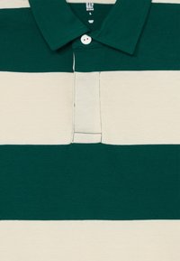 Green and cream striped polo shirt made of cotton, featuring a classic collar, three-button placket, and a soft texture.