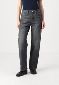 Jean taille haute, coupe droite en denim gris foncé. Comprend un design traditionnel à cinq poches et un léger délavage, assorti à des chaussures noires.