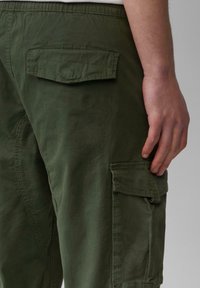 Zielone spodnie cargo o luźnym kroju, z wieloma bocznymi kieszeniami i bawełnianym materiałem o lekko chropowatej powierzchni.
