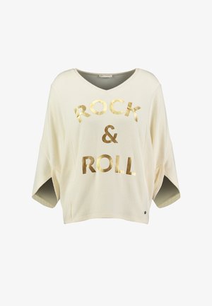 Camiseta de estilo oversized en color crema claro con cuello en V, que presenta texto en dorado "ROCK & ROLL" en la parte frontal y mangas cortas. Textura suave.