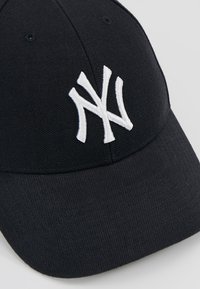 Schwarze Mütze aus strukturiertem Stoff mit einem weißen gestickten "NY"-Logo auf der Vorderseite. Gebogener Schirm, strukturierte Form, sechs Belüftungslöcher.