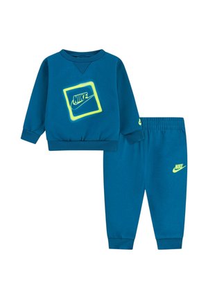 Set felpa e pantaloni blu in morbito cotone. La felpa presenta un grande logo Nike con contorno verde neon; i pantaloni hanno un logo abbinato.