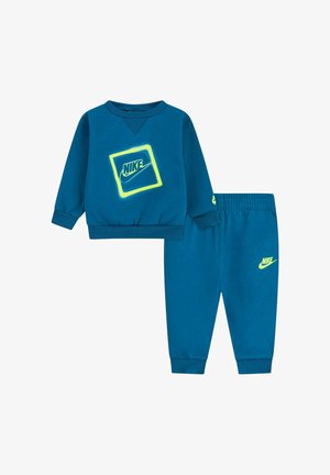 Set felpa e pantaloni blu in morbito cotone. La felpa presenta un grande logo Nike con contorno verde neon; i pantaloni hanno un logo abbinato.