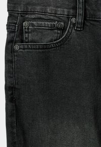Jeans de denim negro con un bolsillo frontal con bordes cosidos y detalles de botón, que muestran una tela texturada y un diseño de corte slim.