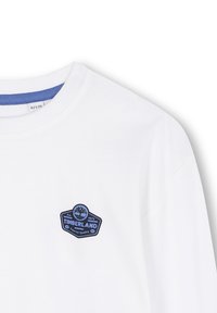 Weißes T-Shirt mit einem blauen Timberland-Logo-Patch auf der linken Brust. Rundhalsausschnitt-Design mit kurzen Ärmeln und einer glatten Stofftextur.