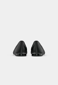 Black leather shoes with a pointed toe design and a low, glossy heel. Smooth texture with visible stitching along the seams.