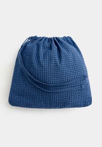 Petit sac à cordon avec un motif à carreaux bleu et noir, fermé en haut, posé sur une surface blanche.